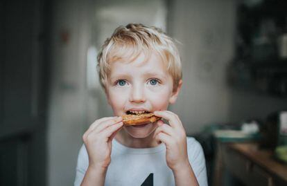 Un niño come una tostada con crema de cacahuete. 