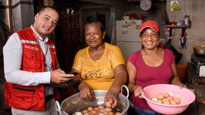 Un asesor de Bancamía, de la Fundación Microfinanzas BBVA en Colombia, atiende a unas clientas en su negocio.