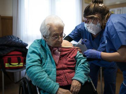 Dos enfermeras vacunan a una anciana.