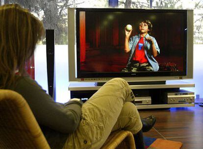 Una mujer viendo un programa en un televisor plano.