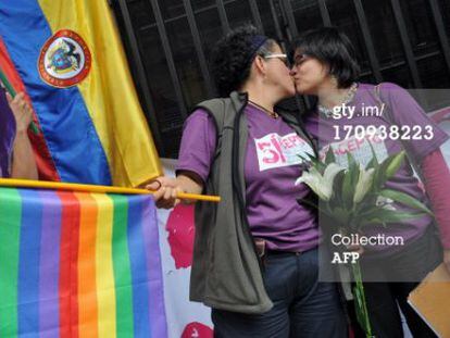 Elizabeth Castillo, con la bandera, besa a su novia Claudia Zea tras presentar los papeles para casarse. 