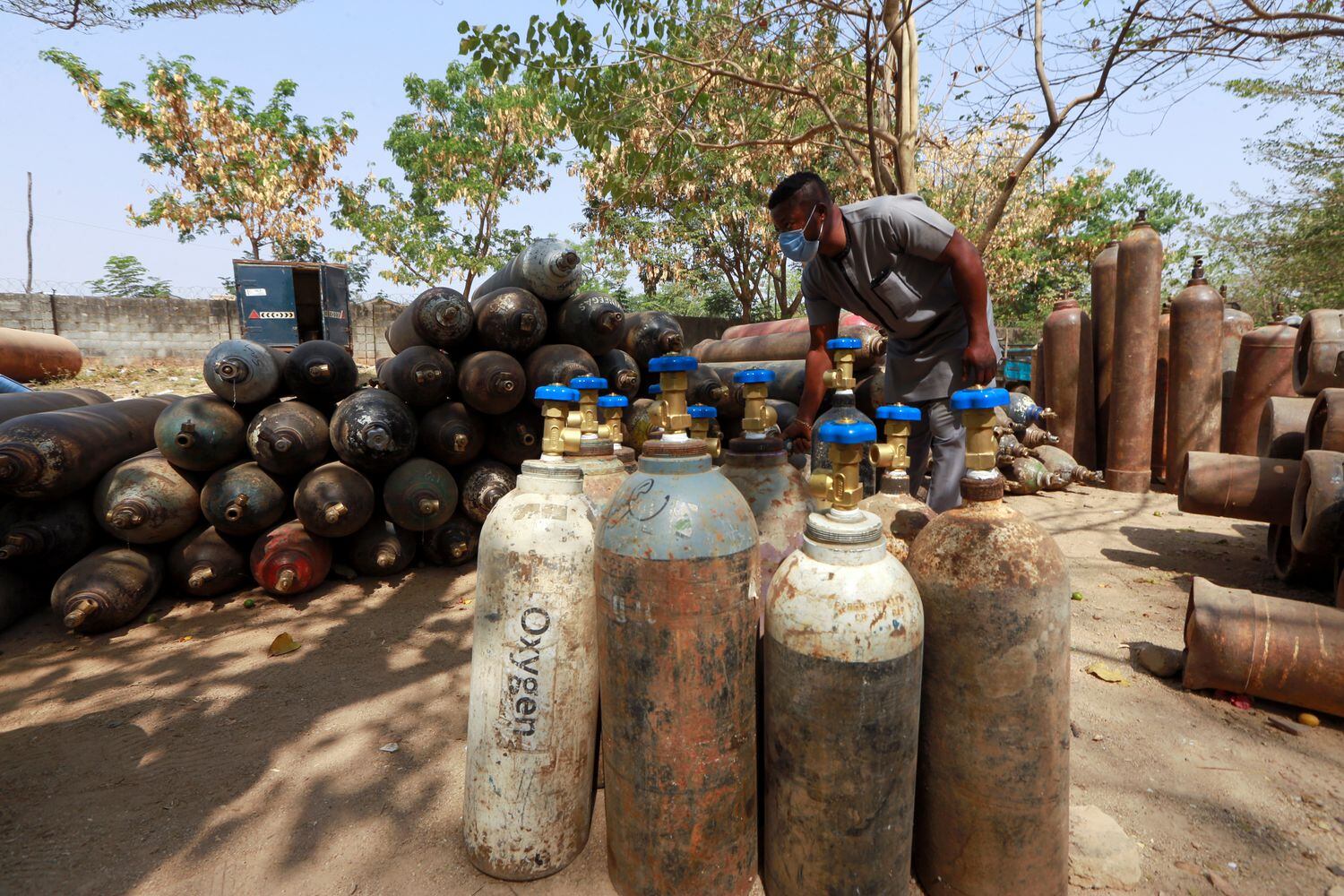 Un hombre inspecciona algunas de sus botellas de oxígeno terapéutico para enfermos de covid-19, dispuestas en el área 1 de la aldea de Gsm, en Abuja (Nigeria).