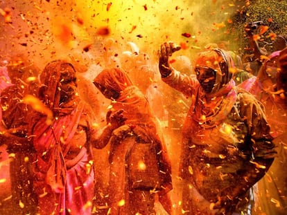 Varias viudas se lanzan polvos de colores y pétalos de flores durante la celebración del festival Holi en la ciudad de Vrindavan (India).