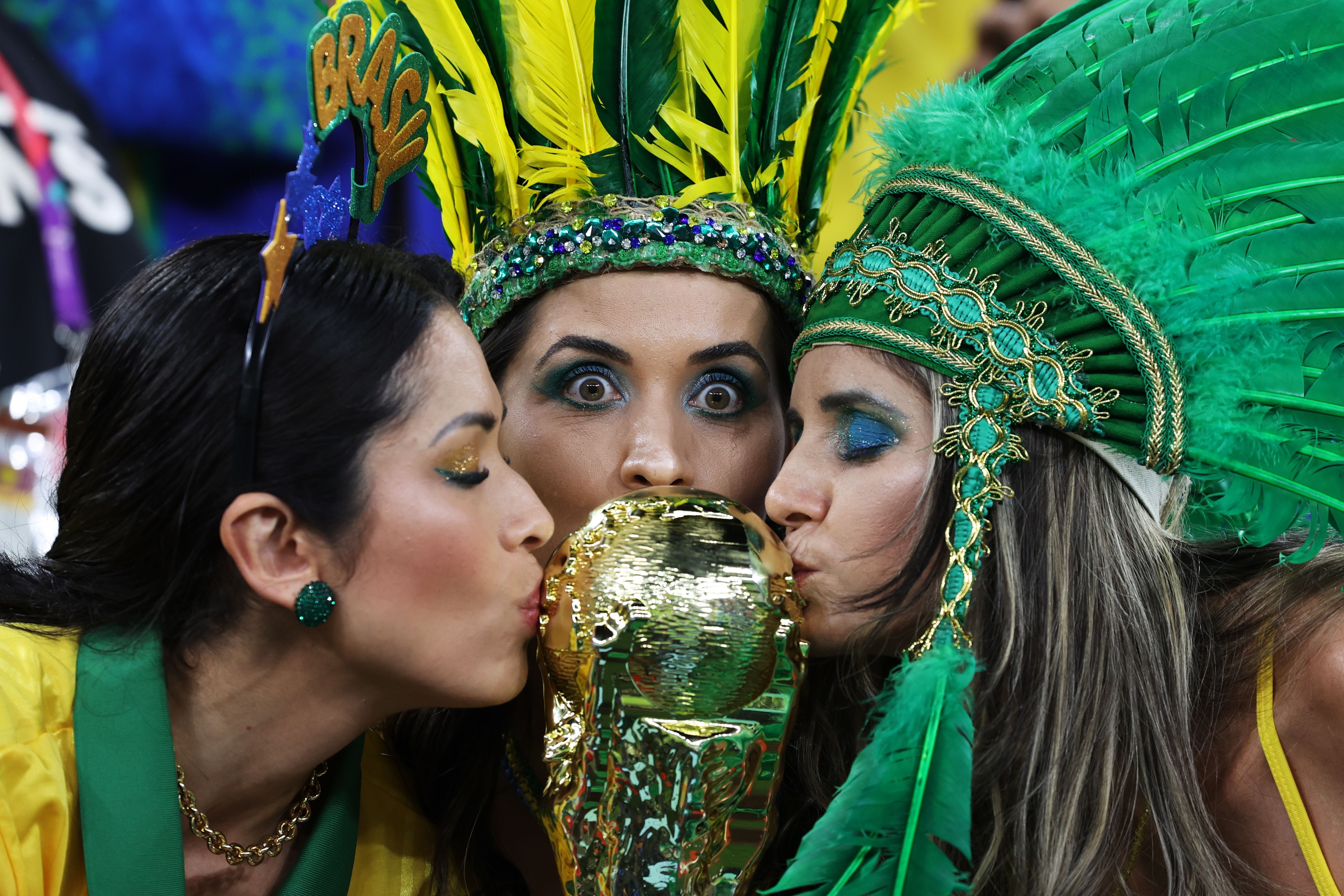 Aficionadas de Brasil besan una Copa del Mundo.