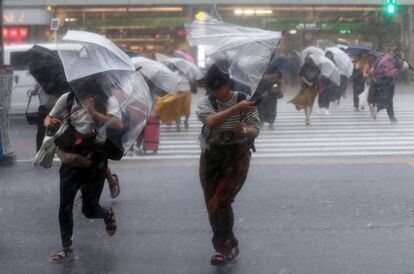 Peatones cruzando un paso entre lluvia y viento en Tokio, este sábado.