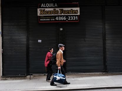 Una pareja camina junto a un antiguo local en renta, en Buenos Aires.