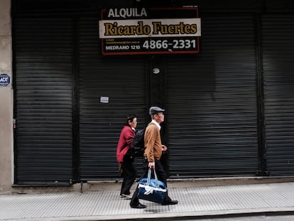 Una pareja camina junto a un antiguo local en renta, en Buenos Aires.