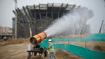 Un trabajador usa una dispositivo que nebuliza agua para tratar de bajar a tierra las particulas contaminantes junto a una obra en la capital india, Nueva Delhi, en 2020.