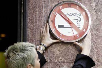 El tiempo corre para el tabaco en el trabajo. Una mujer coloca un reloj alusivo ayer en Bilbao.