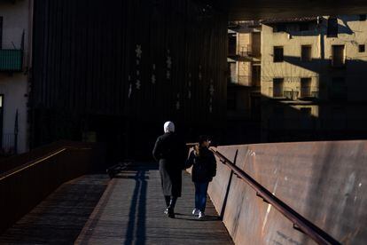 A woman dressed in a veil crosses one of the bridges over the river Ter in Ripoll.