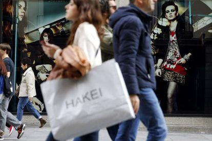 Varias personas pasan con bolsas de compras ante una de las tiendas de la c&eacute;ntrica calle Preciados de Madrid. EFE/Archivo
