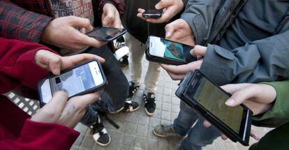 Varios jóvenes conectados a las redes sociales a través de sus teléfonos móviles.