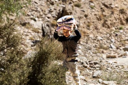 un niño carga ropa que ha llegado en forma de ayuda valle hacia arriba. 
