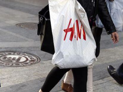 Una mujer pasea por Madrid con una bolsa de H&amp;M. 