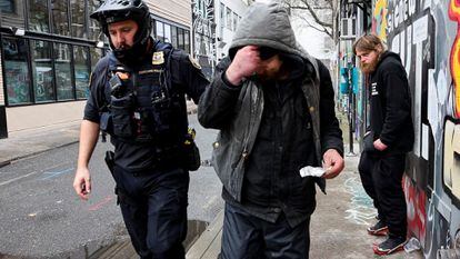 Un oficial de policía entrega un citatorio a un fumador de fentanilo en Portland, Oregón, el 7 de febrero 2024.
