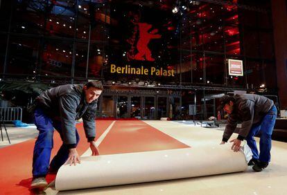 Dos trabajadores desenrollan la alfombra roja a la puerta del Palacio de la Berlinale.
