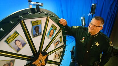 El sheriff Wayne Ivey posa junto a su 'Rueda de fugitivos' en Titusville, Florida, en 2017