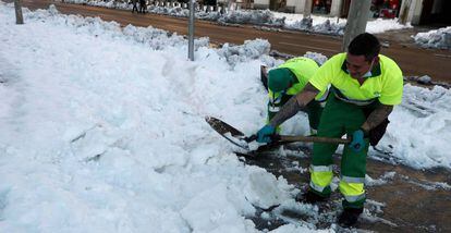Unos operarios retiran nieve acumulada este lunes en la plaza de Colón de Madrid. 