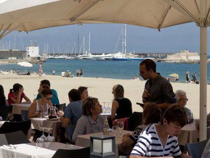Turistas en una terraza frente al mar en Barcelona