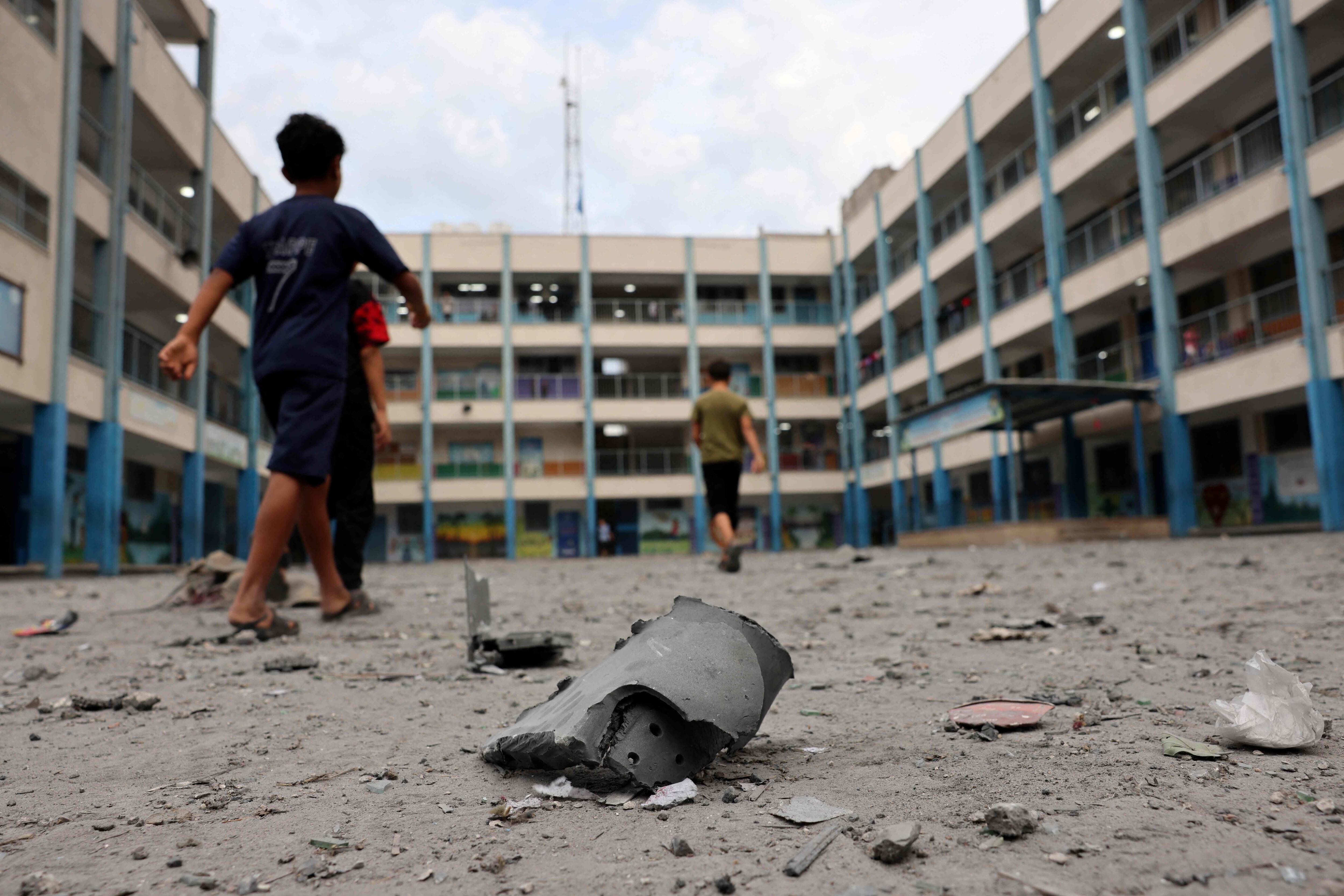 TOPSHOT - Palestian children walks past debris in the courtyard of a school run by the United Nations Relief and Works Agency for Palestine refugees (UNRWA) following Israeli airstrikes targeting Gaza City on October 9, 2023. The Israeli army said it hit more than 500 targets in the Gaza Strip in overnight strikes, as the death toll from its war with Palestinian militants surged above 1,100. (Photo by Mohammed ABED / AFP)