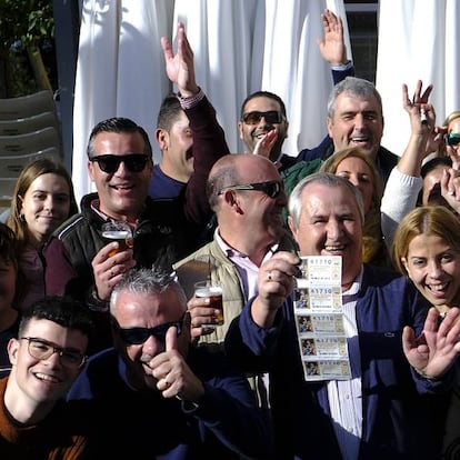 Manuel González, en el centro con cinco décimos, este domingo festejando el cuarto premio de la Lotería de Navidad en Utrera.
