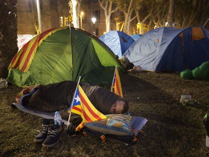 Más de 200 personas han pasado la noche acampadas frente a la sede del Tribunal Superior de Justicia de Cataluña (TSJC), en Barcelona. En la imagen, un hombre duerme entre tiendas de campaña.