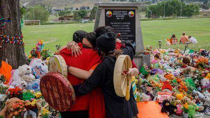 Miembros de la comunidad Mosakahiken Cree Nation se abrazan frente a un monumento en homenaje a las 215 tumbas de niños halladas en el antiguo internado Kamloops para indígenas en Columbia Británica.