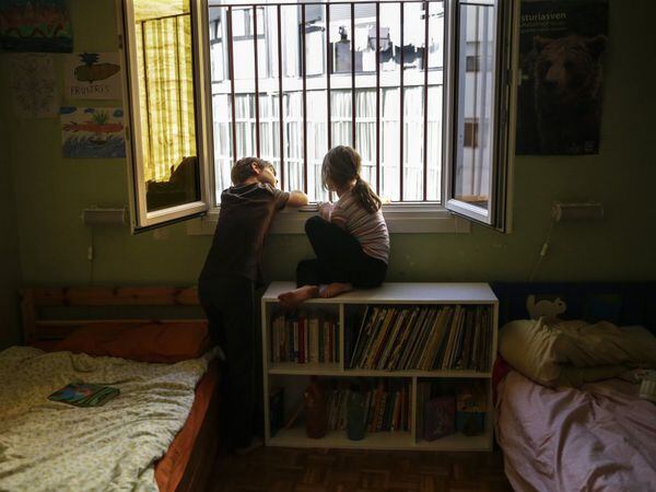 Dos hermanos miran por la ventana de su dormitorio durante el confinamiento en Madrid, el 13 de abril. Ansiedad, obesidad, y somatizaciones del estrés son los problemas frecuentes. Sanidad encarga a la Asociación Nacional de Pediatría un informe para estudiar las condiciones de salida de los menores.