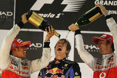 Lewis Hamilton y Jenson Button, de McLaren Mercedes, remojan al vencedor de la carrera y del Mundial, Sebastian Vettel, en el podio.