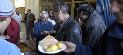 Un voluntario reparte comida a varios hombres en el Banco de Alimentos de Jaén.