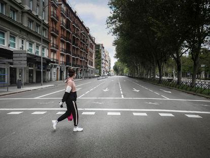 Una mujer cruzando un vacío Paseo del Prado de Madrid, durante el estado de alarma.