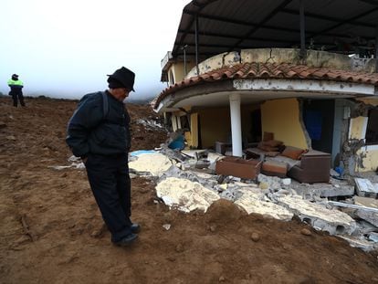Pobladores observan los daños causados por un deslizamiento de tierra, en Alausí.