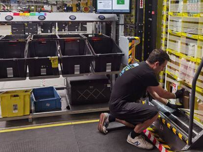 Un trabajador de Amazon introduce productos en las estanterías que le acercan los robots a su puesto de trabajo.