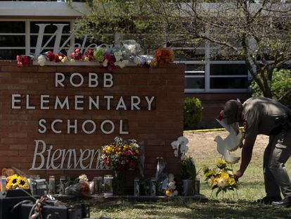 Un oficial coloca flores a las afueras de la Escuela Primaria Robb en Uvalde, Texas después del tiroteo.
