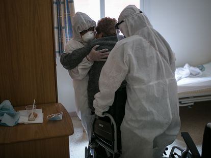 Dos sanitarios ayudan a una anciana en una residencia