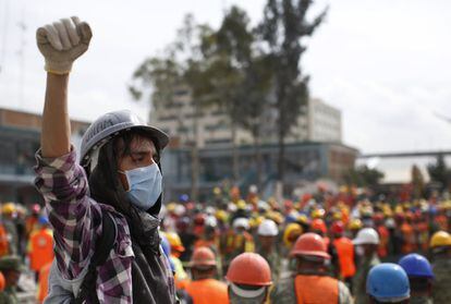 Un joven voluntario levanta su puño para pedir silencio mientras los perros de rescate buscan entre los escombros tras el terremoto en Ciudad de México.