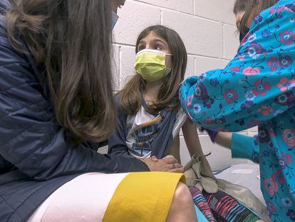 Alejandra Gerardo, de nueve años, mira a su madre mientras la vacunan contra la covid en el hospital universitario de la Universidad de Duke. Alejandra y su hermana gemela Marisol son las primeras niñas en recibir la vacuna de Pfizer en EE UU.