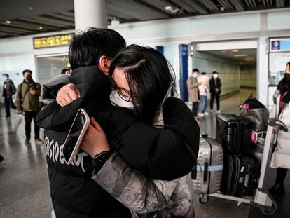 Dos personas se abrazan este domingo en la zona de llegadas en el aeropuerto internacional de Pekín.