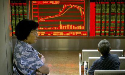 Dos inversores observan pantallas con informaci&oacute;n financiera este mi&eacute;rcoles en Shangh&aacute;i.