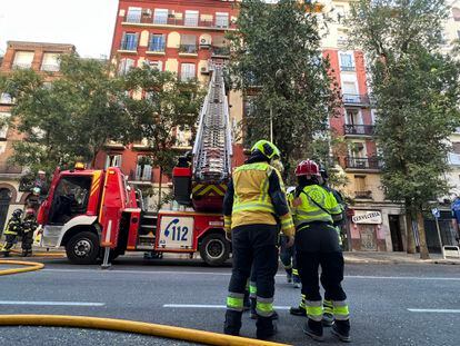 Varios bomberos, durante las labores de extinción del incendio declarado esta mañana en una vivienda de Chamberí.