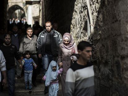 Fieles palestinos caminan junto a soldados armados en la Ciudad Vieja de Jerusal&eacute;n, el viernes