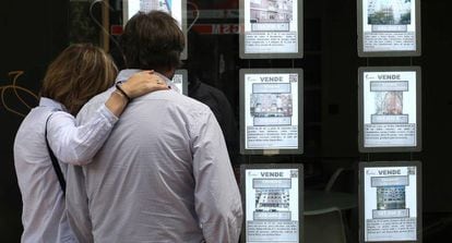 Una pareja observa anuncios de pisos en una inmobiliaria en Madrid