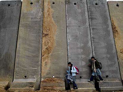 Dos niñas palestinas circulan cerca de Ramala ante el muro de separación levantado por Israel.