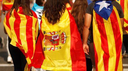 Tres jóvenes acuden a una manifestación en Barcelona con una senyera, una bandera de España y una estelada.