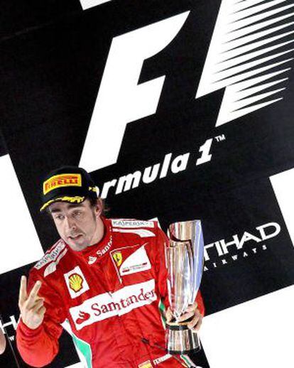 Fernando Alonso sostiene el trofeo en el podio de Abu Dabi.