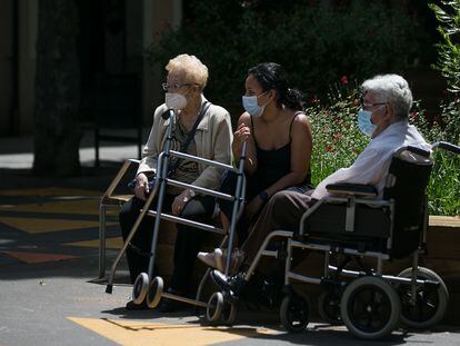 Dos ancianos junto a una joven toman el aire en el barrio de Sant Antoni, en Barcelona, el pasado junio.