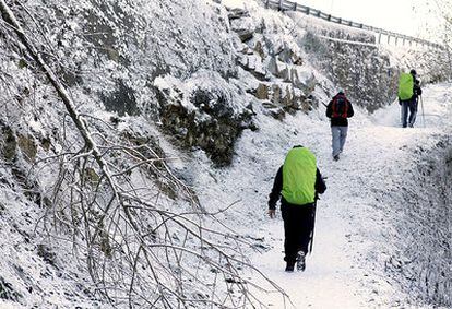 Un grupo de peregrinos camina bajo la nieve en Lugo