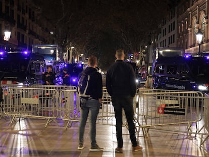 Dos jóvenes contemplan varias furgonetas de los Mossos de Esquadra antes de la llegada de los Reyes en el Liceu.