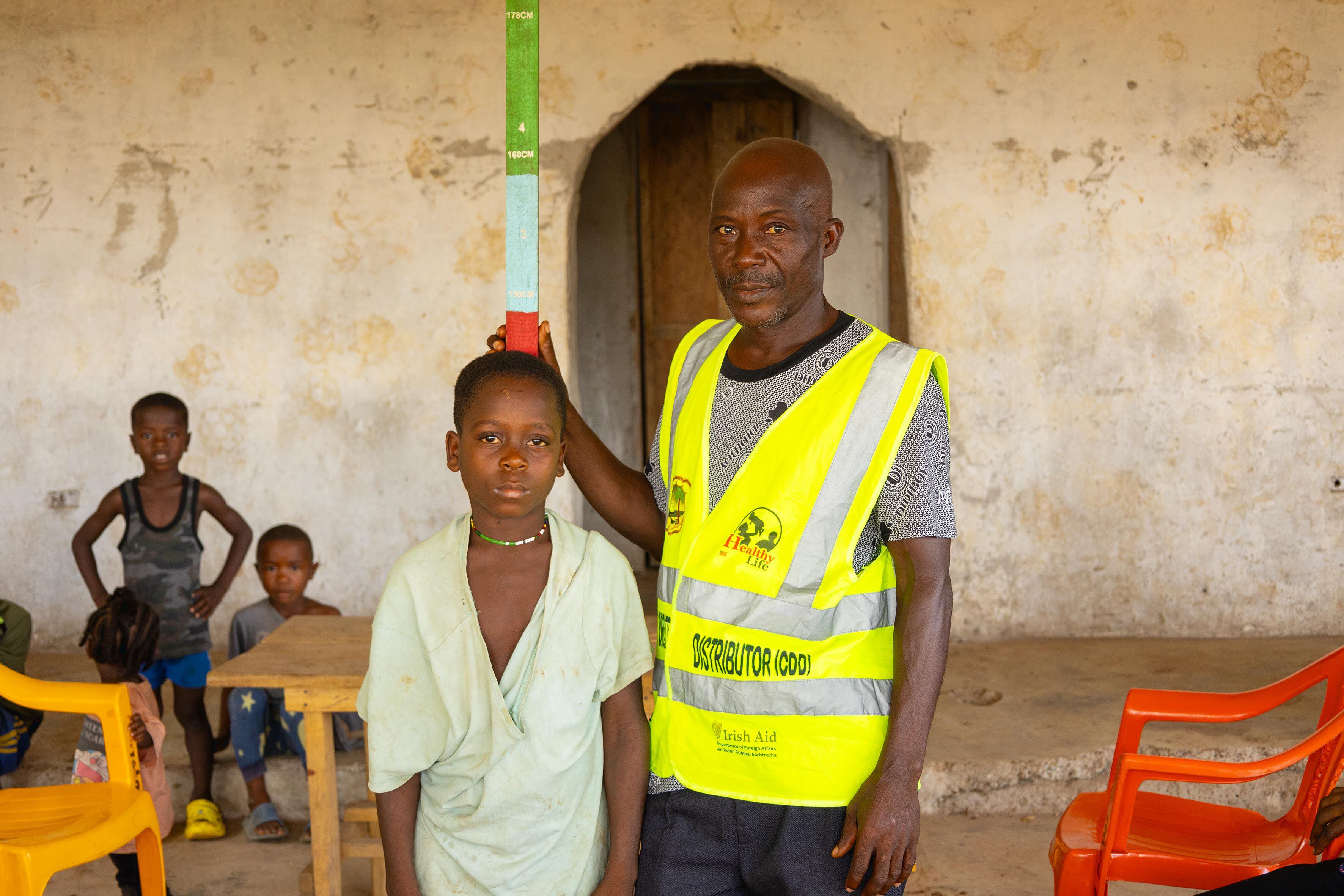 Abraham Kallie, de 45 años, es voluntario de salud en su comunidad, en Febe, en el condado de Bong (al norte de Liberia). Con una vara de 1,8 metros de colores, calcula la dosis de medicamentos que tiene que recibir cada niño para prevenir enfermedades parasitarias.