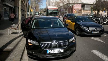 Un usuario de Cabify junto a un taxi, en Barcelona.